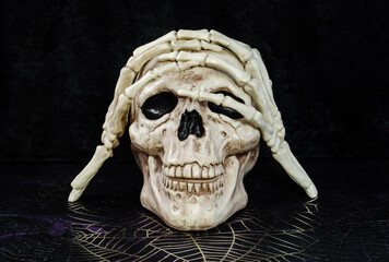 A skull halloween decoration and skeleton hands posing
