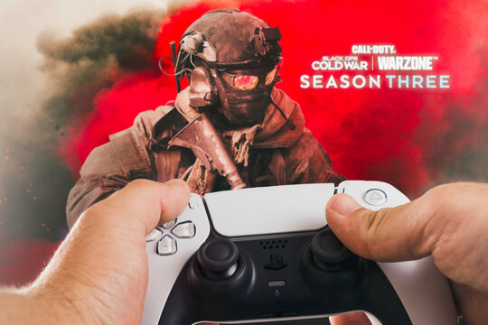 Male hand holding a Playstation 5 Dual Sense Controller with Call of Duty Season Three game blurred in the background. Rio de Janeiro, RJ, Brazil. October 2021.