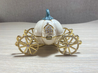 Statuette in the form of a pumpkin carriage on golden wheels close-up