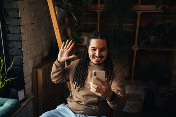 Young man hipster using his smartphone, sitting in a coffeehouse and drinking coffee.