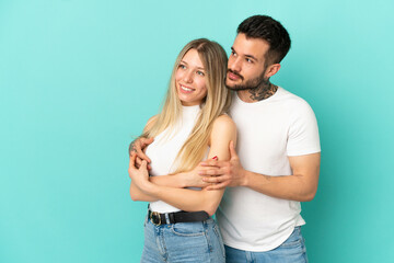 Young couple over isolated blue background looking to the side