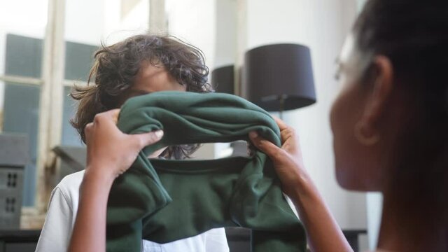 Slow motion of mother helping boy put on school jumper