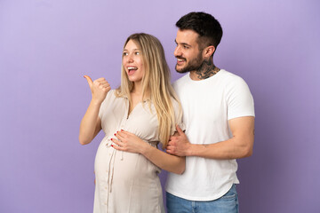Fototapeta premium Young couple pregnant and pointing to the lateral