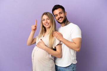 Young couple pregnant and pointing up