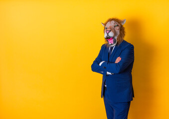 Businessman with lion mask with arms crossed. Copy space on yellow background.