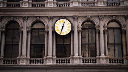 A traditional analog clock with yellow numbers on the front of an old office building in SoHo, Manhattan, New York. 