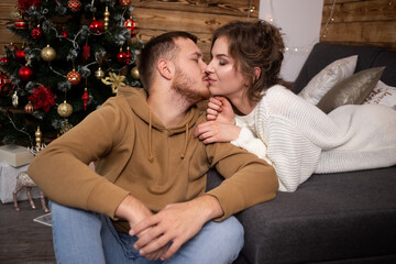 Sweet couple kissing in front of a Christmas tree.