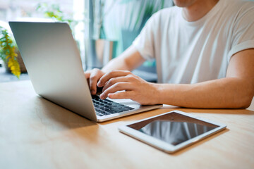 An employee counts finances in an online table. A man works in a cafe on a laptop. Writes an email to clients.
