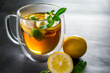 Tea with lemon and mint in transparent cup. Alternative medicine for treatment.