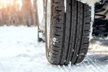 Close-up detail view of car wheel with unsafe summer tread tire during driving through slippery...