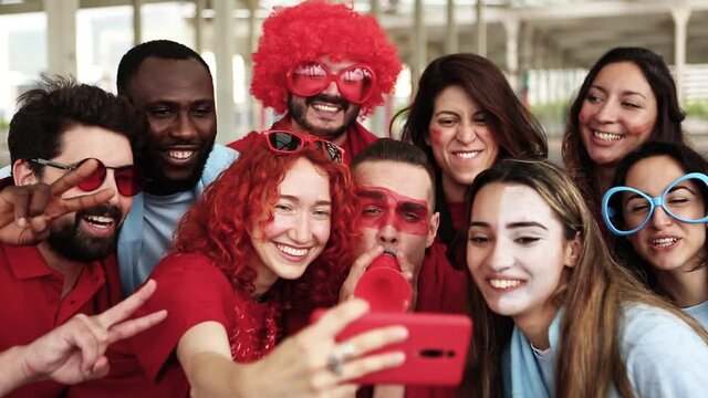 Group of multiracial supporter sport fans taking selfie with mobile phone while supporting their football team - Young people having fun outside the stadium