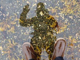 Photographer takes self portrait in shallow intertidal water wearing XTRATUF boots and waving