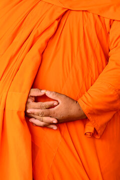 A Buddhist monk in Cambodia with folded hands and saffron robe