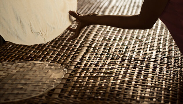 A South Vietnamese woman puts wet rice paper onto a wicker drying rack