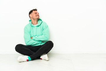 Young handsome caucasian man sitting on the floor happy and smiling