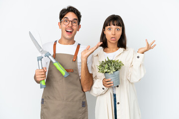 Young mixed race gardeners holding a plant and pruning shears isolated on white background with...
