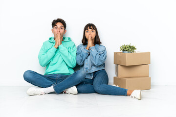 Young couple making a move while picking up a box full of things sitting on the floor isolated on...