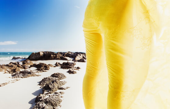 wearing yellow sarong standing on rocky beach