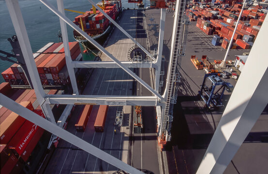 Looking down from crane at wharf full of shipping containers and loaded ships in Port