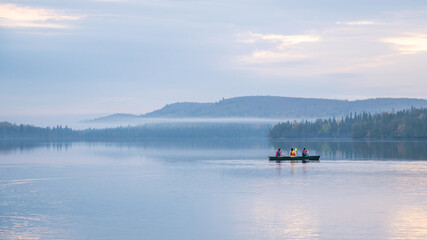 People are boating on Caribou Lake on a fogy morning