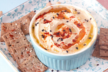 hummus with paprika and sesame seeds in a blue bowl