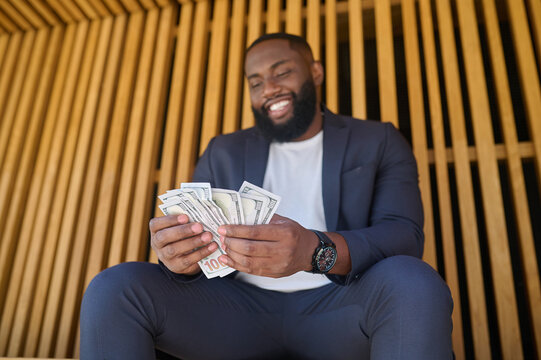 A man sitting on the bench and holding dollars in hands
