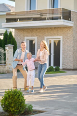 Naklejka premium Cheerful little girl with dad and mom on street