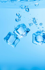 Ice cubes in blue water create bubbles that float to the surface, blue liquid.