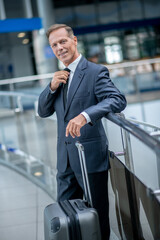 Man in suit straightening tie in airport lounge