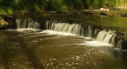 Obraz premium Small river with woods, rocks and waterfall.