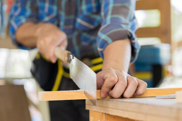 Carpentry professional, asian young man, male carpenter use machines or tool, knife saw to cut board, wood in small shop. Woodwork, furniture making, construction industry. Owner small business people
