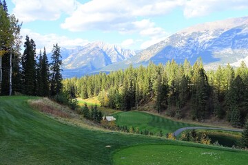 A beautiful view of a par 3 golf hole on a course with mountains in the background, surrounded by...