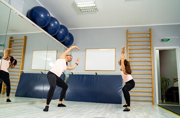 Fototapeta premium Two woman in gym doing ballet stretches 