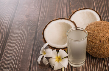 Glass of coconut water and coconut om wooden table.