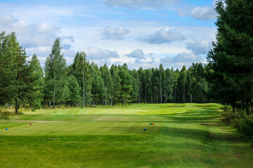 Obraz premium Golf course, landscape, green grass on the background of the forest and a bright sky with clouds. High quality photo
