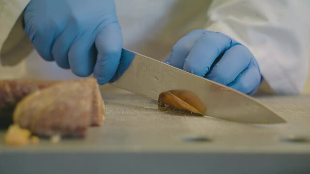 Person With Blue Gloves Slicing Thin Slices of Bottarga, Delicacy Of Salted, Cured Fish Roe. - close up