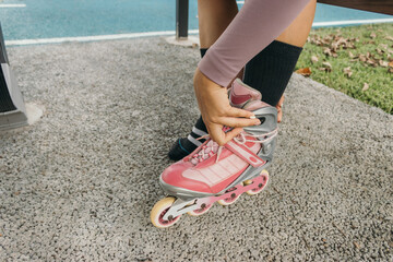 Hispanic young adult woman fitting on her rollerblades at the park close up