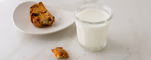 a glass of milk and cantucci cookies on a light marble table
