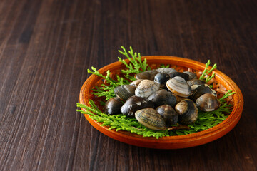 ざるに盛ったアサリ　木目背景