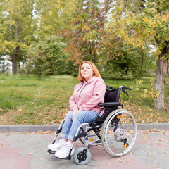 Fototapeta na wymiar disabled teenage girl on a wheelchair for a walk in the autumn park. A full life for people with disabilities. Walking in the autumn park. Outside home. 