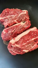 Roasting meat for dinner or lunch. Classic selected beef steak. Two pieces of juicy pork on a black background. Cooking meat in a pan at home. The benefits of protein products for humans.
