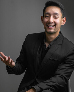 Portrait Of A Handsome Cheerful East Asian Businessman Wearing A Suit In A Studio