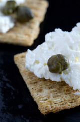 Macro Image of Wheat Cracker with Feta Cheese and Caper on Dark Background