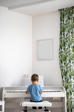 Cute baby boy playing white electrical forte piano pressing keys kid studying at musical school