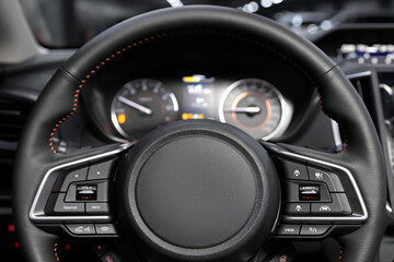 Salon of a new stylish car, steering wheel , dashboard with speedometer, tachometer and other setting buttons.