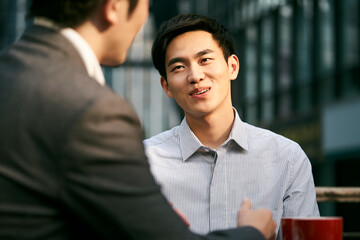two asian business men meeting in outdoor cafe