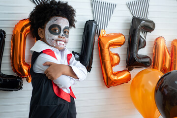 Little dark skinned boy in Dracula costume celebrate Halloween, making scary gesture at camera, Happy Halloween concept