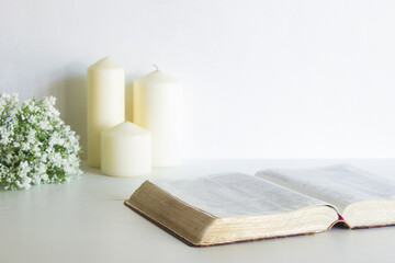 Bible with candles and flowers on table with nature light.