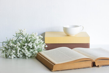 Books with coffee and flowers on table with nature light. 