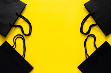 Black shopping paper bags on yellow background for Black Friday shopping sale concept.